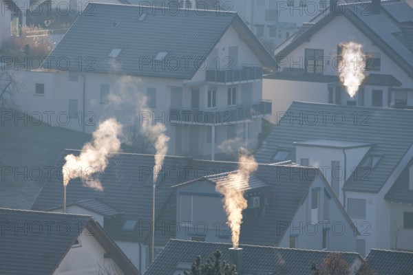 Sunrise over a village with smoking chimneys, calming morning atmosphere, symbolic image,