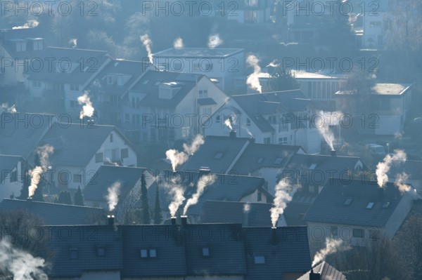 Cold winter morning view of a settlement with numerous smoking chimneys, symbolic image,