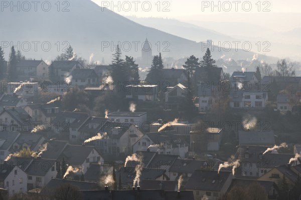 Extensive village panorama with smoking chimneys and hills in the morning haze, symbolic image,