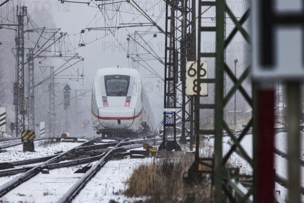 ICE traveling through a winter landscape in snowfall. A train on the line in the Deutsche Bahn