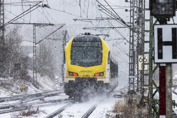 Regional train from Arverio on its way through a winter landscape in snowfall. The railcar train is