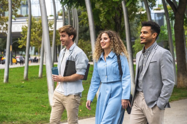 Three diverse business professionals, two men and one woman, walking and conversing outdoors in a