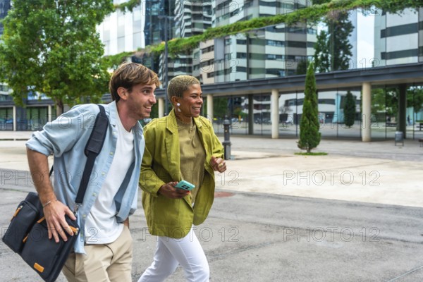 Diverse business professionals walking and discussing in a modern urban area, holding a bag and