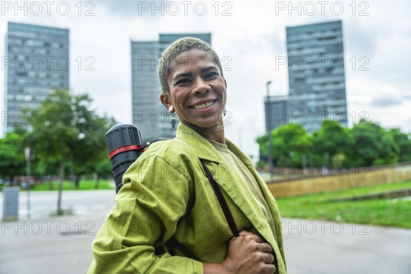 Urban architect smiling confidently with drawing tube on shoulder strap, standing in front of