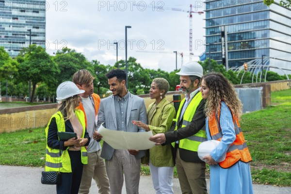 Group of multi ethnic architects, engineers, and executives reviewing blueprints and discussing