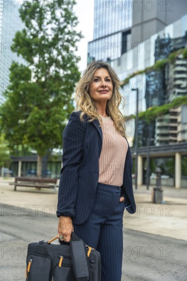 Confident businesswoman wearing a pinstripe suit, holding a briefcase and looking forward, standing