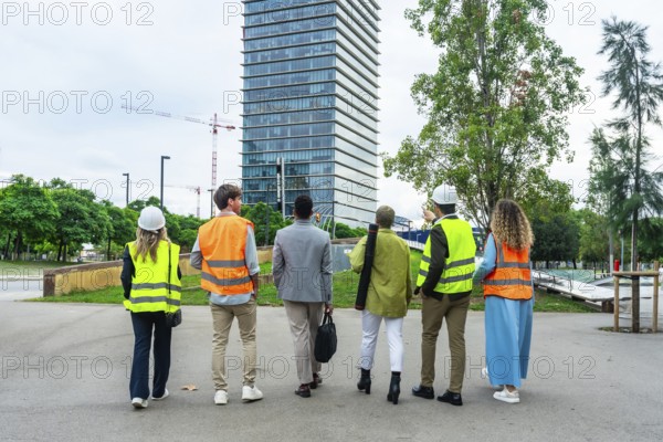 Diverse team of engineers, architects, and business executives standing with backs to camera,