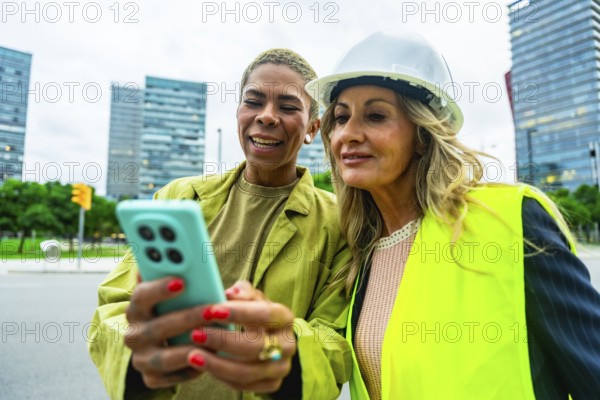 Diverse women architects and engineers smiling and collaborating outdoors in a modern city, using a