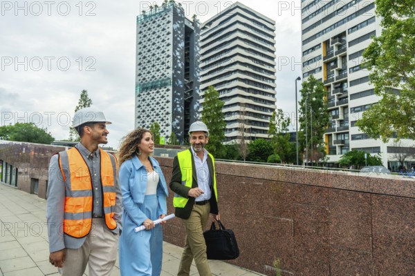 Diverse team of engineers and executives wearing safety vests and hard hats walking outdoors in a