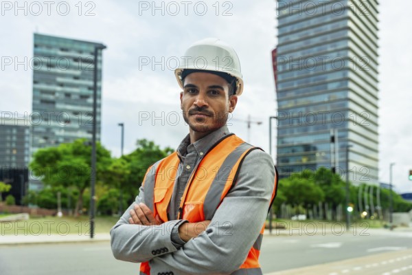 Professional engineer or architect standing confidently with crossed arms, wearing a hardhat and