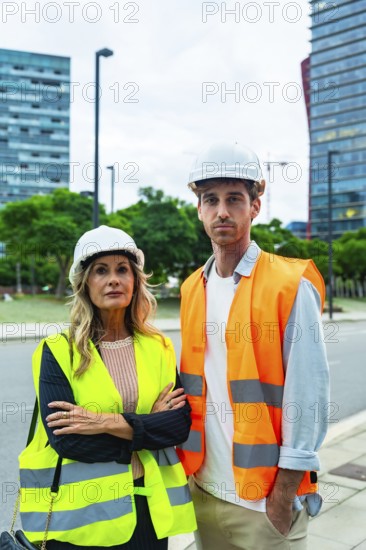 Construction professionals wearing hard hats and reflective vests, standing outdoors, collaborating