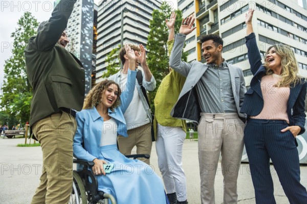 Diverse business colleagues including a woman in a wheelchair cheering and doing high fives