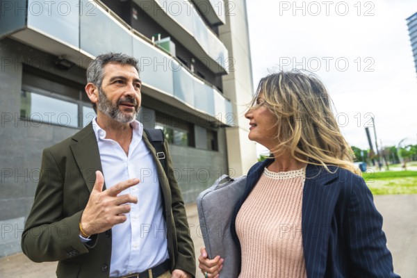 Two business colleagues, a man and a woman, are walking and having a professional discussion