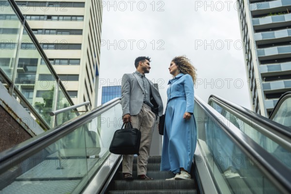 Two business professionals ascending an escalator, engaging in a conversation with modern