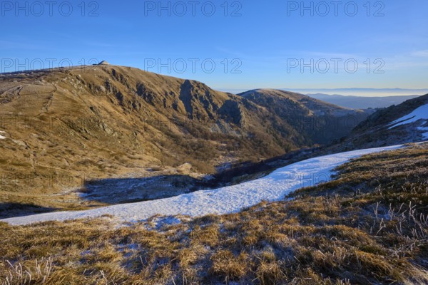 Extensive valley in the mountains, snowy, with clear skies and morning light, winter, Route de