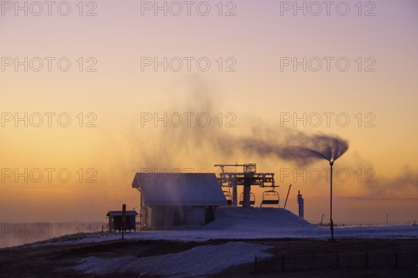 Snow cannons produce fog in orange sunset, winter, Route de Cretes, Hohneck, La Bresse, Vosges,