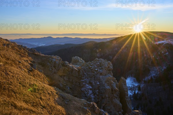 View of a rock formation illuminated by the low sun in the mountains, looking towards the Rhine