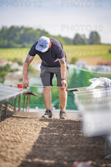 A worker on a construction site measures something while installing solar systems, new park and