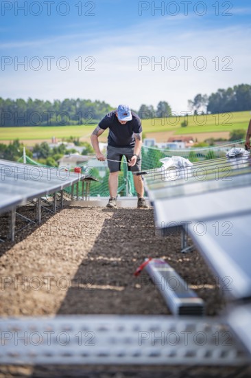A technical worker installs solar panels on a construction site with a rural background, new Park