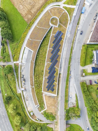 Aerial view of a building with solar panel, surrounded by roads and green vegetation, new park and