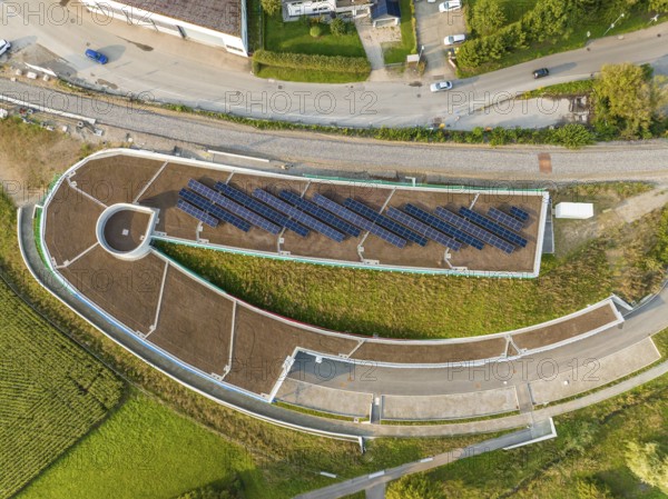 Aerial view of a solar cell field on a roof with surrounding roads, new Park and Ride parking