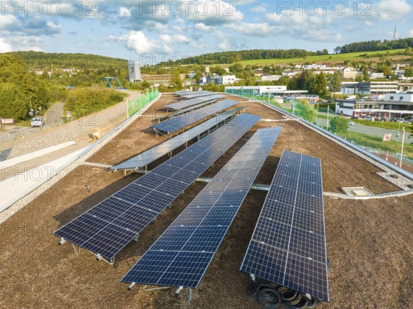 Arrangement of solar modules in a rural area with houses and hills, new park and ride parking