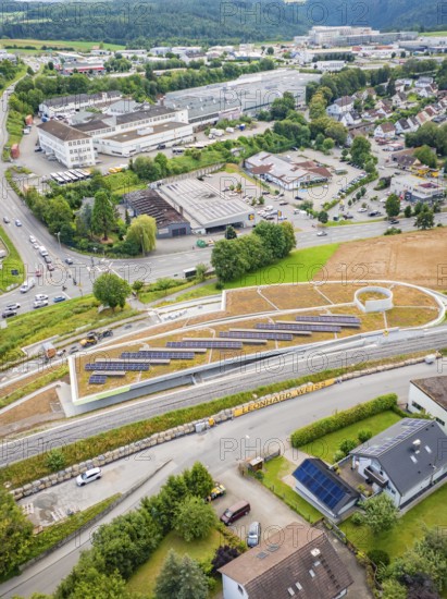 Overview of solar panels on a hill in an urban area with surrounding roads, new park and ride