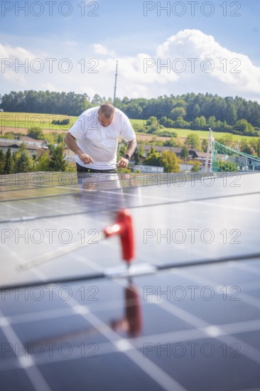 Worker checking solar modules in a landscaped area with clear skies, new park and ride Calw