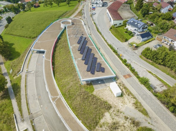 Large solar panel system on roof surrounded by rural village and greenery, new park and ride