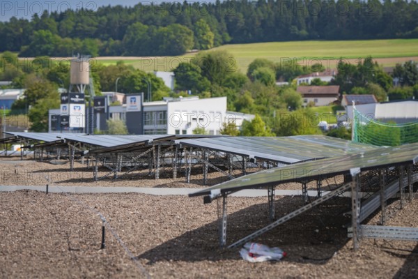 Solar panels on a roof with a view of a green landscape and nearby buildings, new park and ride