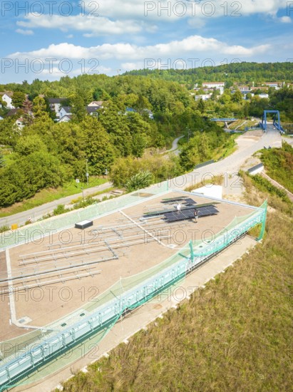 Aerial view of a construction site with solar system and surrounding green landscape in the