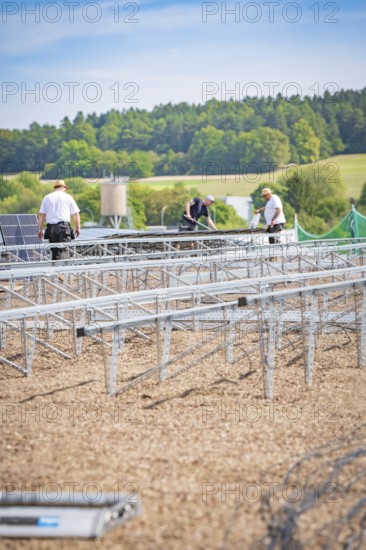 Several workers install solar panels on large racks in a scenic area, new Park and Ride Calw