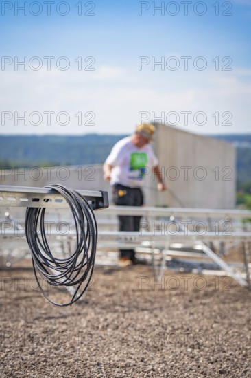 Cable against a blurred background showing workers installing a solar system, new park and ride