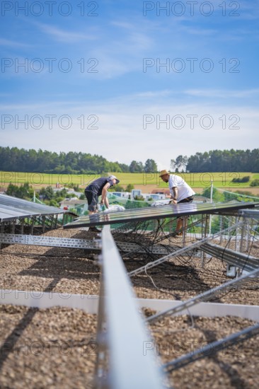 Two workers install a solar system surrounded by a quiet landscape under blue skies, new park and