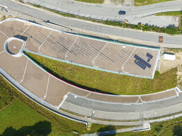 Aerial view of a green roof with solar panel and surrounding roads in urban surroundings, new park