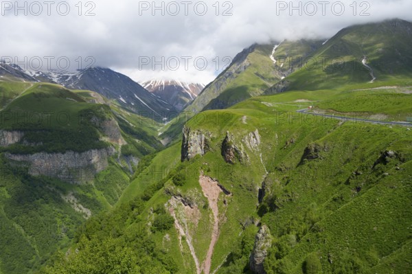 Green mountain landscape with visible road and gorges, cloudy weather, mountainous landscape