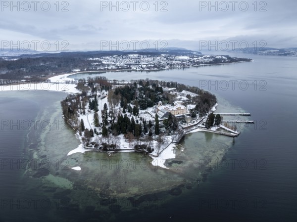 The wintry and snowy Mainau island in Lake Constance with the pier and the baroque Mainau Castle,