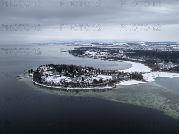 The wintry and snowy Mainau island in Lake Constance with the boat dock and the baroque Mainau