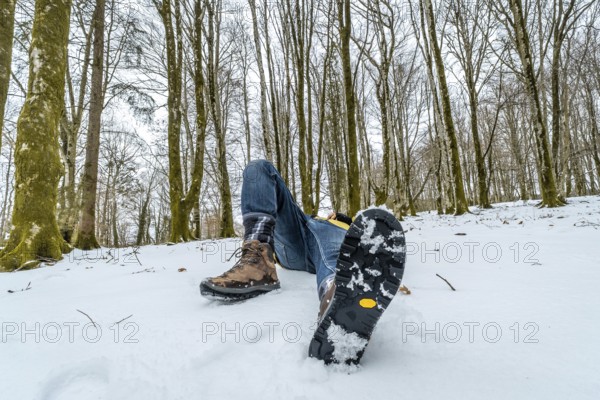Person lying down in deep snow wearing warm hiking boots with a visible non slip sole, experiencing