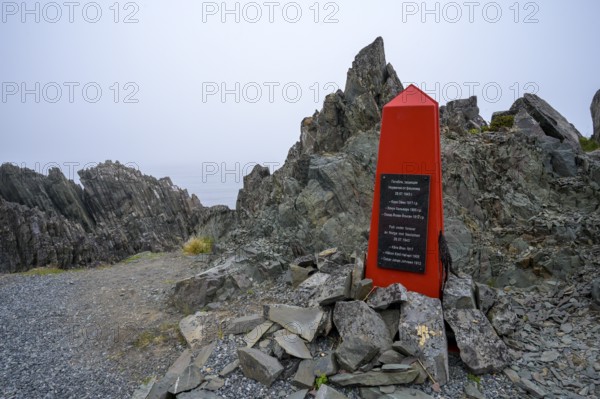 Red memorial to resistance fighters from the Second World War on rough rocks with fog in Norway,