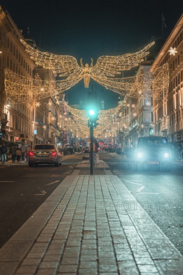 Festively illuminated street with Christmas decorations and cars at night, London, England, Great