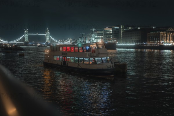 Illuminated boat on the Thames at night with Tower Bridge in the background, London, England, Great