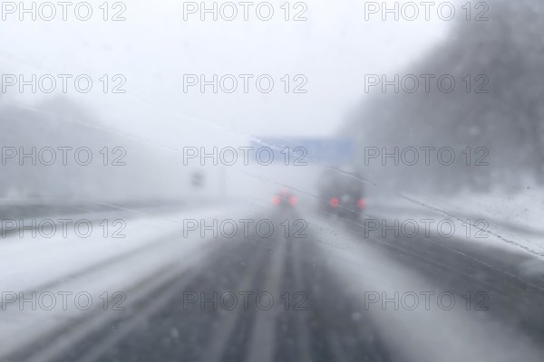View through fogged windshield of cars driving through light snowblowing on partially covered