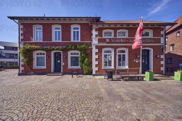 Tourist information, advertising flags on flagpoles, brick buildings, houses, bench, walkway made