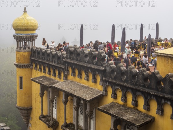 Tourists visiting the palace Palácio Nacional da Pena, foggy day, Sintra, Portugal