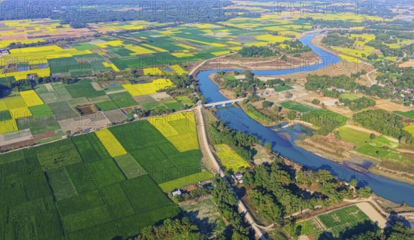An aerial view reveals a gently curving river winding through the countryside, its silvery surface
