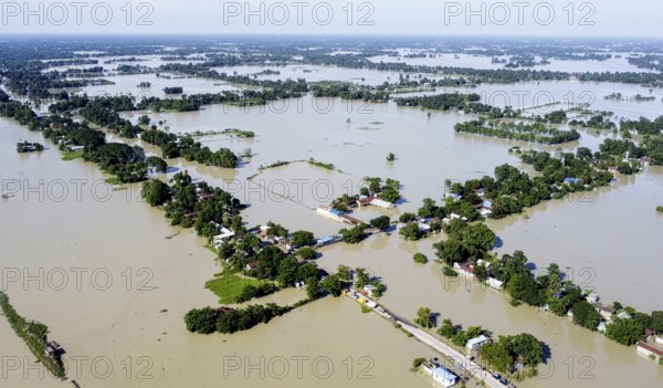 An aerial view shows widespread flooding submerging villages and farmland, with isolated homes and