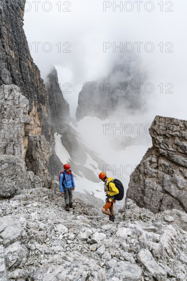 Two mountaineers in rocky, cloudy mountain landscape at Bochetta Bassa del Massodi, Brenta