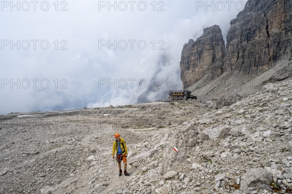 Mountaineers on a hiking trail in a rocky, cloud-covered mountain landscape while descending to