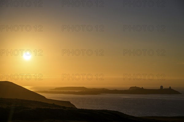 Midnight sun on Mount Domen in the background the city of Vardø, sea at sunset with golden sky and